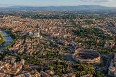 Aerial view of Rome showing the historic center, dense neighborhoods, rail lines, green space, and outer development