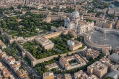 High aerial view of Vatican City showing Saint Peter Square, basilica, gardens, walls, and surrounding Rome